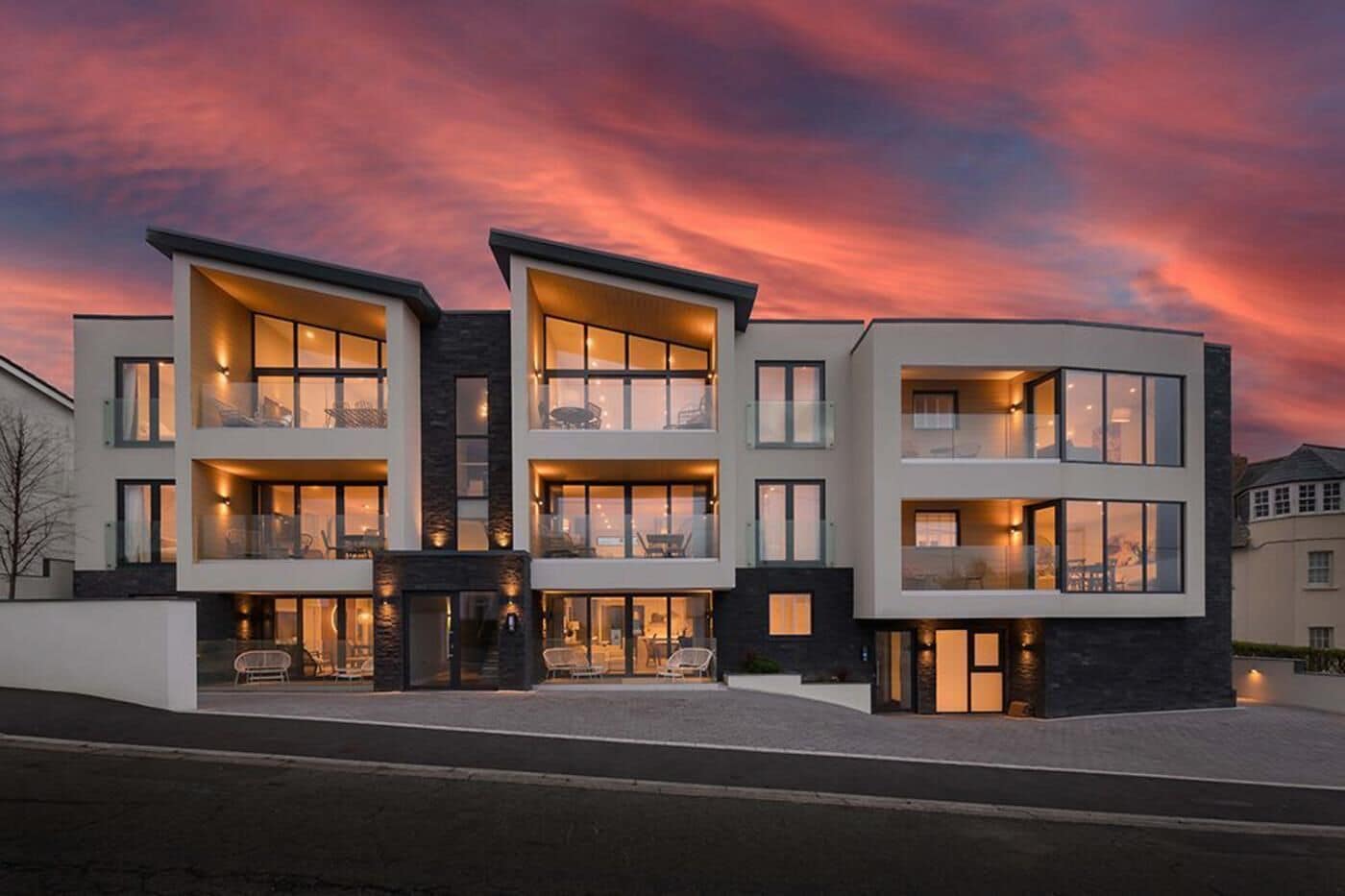 A modern multi-story residential building with balconies and large windows.