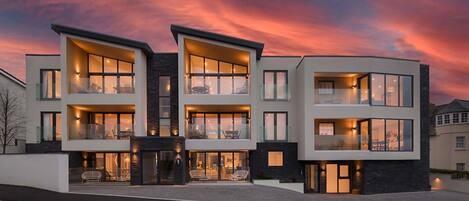 A modern multi-story residential building with balconies and large windows.