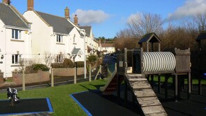 A playground with a slide, climbing area, and a small table. - 3 Bed in Bridport (oc-b45261) (Bridport)