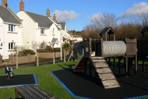 Ein Spielplatz mit Rutsche, Kletterbereich und einem kleinen Tisch.