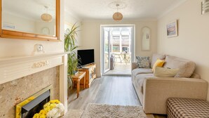 A living room with a fireplace, television, sofa, and a view of the outside. - 3 Bed in Bridport (oc-b45261) (Bridport)