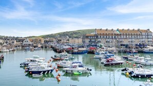 A harbor with numerous boats docked, buildings in the background, and a clear sky. - 3 Bed in Bridport (oc-b45261) (Bridport)