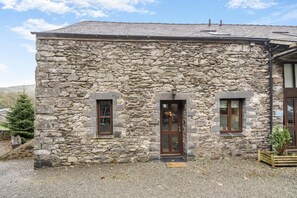 Ein Steinhaus mit einem zentralen Eingang und je einem Fenster auf beiden Seiten, mit einem Schild, das es als Herberge kennzeichnet.