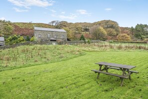 A stone building with a grassy field and a picnic table in the foreground. - 5 Bed in Grizebeck (oc-b34029) (Kirkby Ireleth)