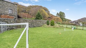 A grassy outdoor area with a goalpost, stone wall, and a stone building. - 5 Bed in Grizebeck (oc-b34029) (Kirkby Ireleth)