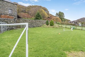 A grassy outdoor area with a goalpost, stone wall, and a stone building. - 5 Bed in Grizebeck (oc-b34029) (Kirkby Ireleth)