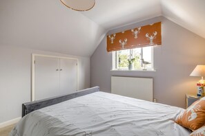 Une chambre à coucher avec un lit, une fenêtre donnant sur un beau paysage, un radiateur et une armoire.
