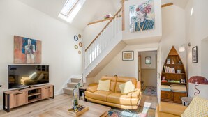 A spacious living room with a large flat-screen TV, a leather sofa, a wooden coffee table, and a staircase leading to an upper level. - 1 Bed in Dunblane (oc-j36313) (Bannockburn)