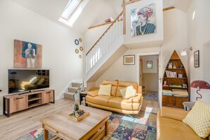 A spacious living room with a large flat-screen TV, a leather sofa, a wooden coffee table, and a staircase leading to an upper level. - 1 Bed in Dunblane (oc-j36313) (Bannockburn)