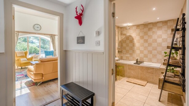 A modern interior with a living area featuring a sofa and a coffee table, a kitchen with a sink and tiled backsplash, and a red deer head decoration on the wall. - 1 Bed in Dunblane (oc-j36313) (Bannockburn)