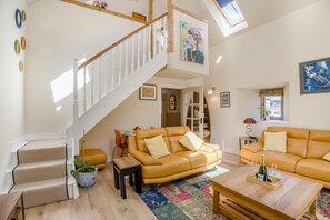 Ein geräumiges Wohnzimmer mit hoher Decke, einer Treppe und Blick zum Himmel.