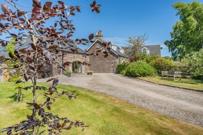 A stone house with a gravel driveway and a bench in the yard. - 1 Bed in Dunblane (oc-j36313) (Bannockburn)