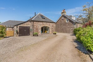 A stone building with a gravel driveway, a wooden gate, and a clear sky. - 1 Bed in Dunblane (oc-j36313) (Bannockburn)