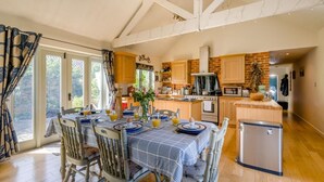 A dining area with a table set for breakfast, a kitchen with modern appliances, and a view through the window. - 3 Bed in Briningham (oc-s44878) (Briningham)