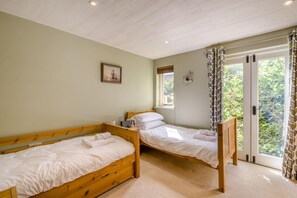 A bedroom with two wooden beds, a window with a view of greenery, and a door leading outside. - 3 Bed in Briningham (oc-s44878) (Briningham)