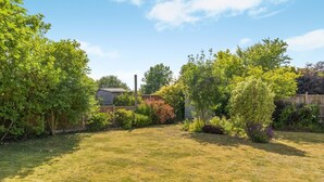 A backyard with a wooden fence, a shed, and various shrubs and trees. - 3 Bed in Briningham (oc-s44878) (Briningham)