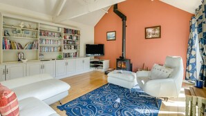 A living room with a fireplace, white furniture, a bookshelf, and a television. - 3 Bed in Briningham (oc-s44878) (Briningham)