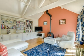 Ein Wohnzimmer mit Kamin, weißen Möbeln, einem Bücherregal und einem Fernseher.