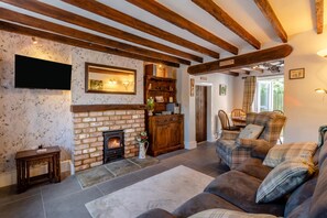 A cozy living room with a fireplace, wooden beams, and a plaid sofa. - 2 Bed in Melton Mowbray (oc-h45352) (Hose)