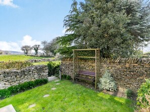 A stone wall, a wooden pergola, and a bench in a garden setting. - 2 Bed in Scarborough (oc-36571) (Ebberston)