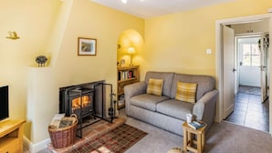 A cozy living room with a fireplace, a sofa, a lamp, and a bookshelf.