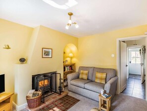 A cozy living room with a fireplace, a sofa, a lamp, and a bookshelf.