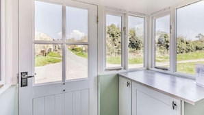 A room with a large window overlooking a rural road, a white door, and a light-colored countertop.