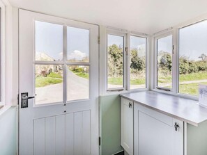 A room with a large window overlooking a rural road, a white door, and a light-colored countertop.