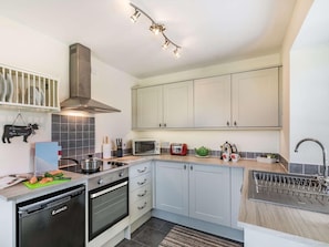 A modern kitchen with a dishwasher, oven, microwave, and a hanging light fixture.