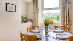A dining table set for four with chairs, a vase with flowers, and a window with curtains. - 2 Bed in Sedbusk (oc-l44913) (Sedbusk)