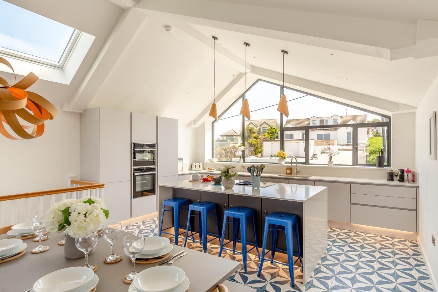 A modern kitchen with a large island, bar stools, and a dining area with a table set for six.