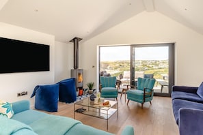 Un salon moderne doté d’une cheminée, de sièges confortables et d’une grande fenêtre offrant une vue sur la campagne.