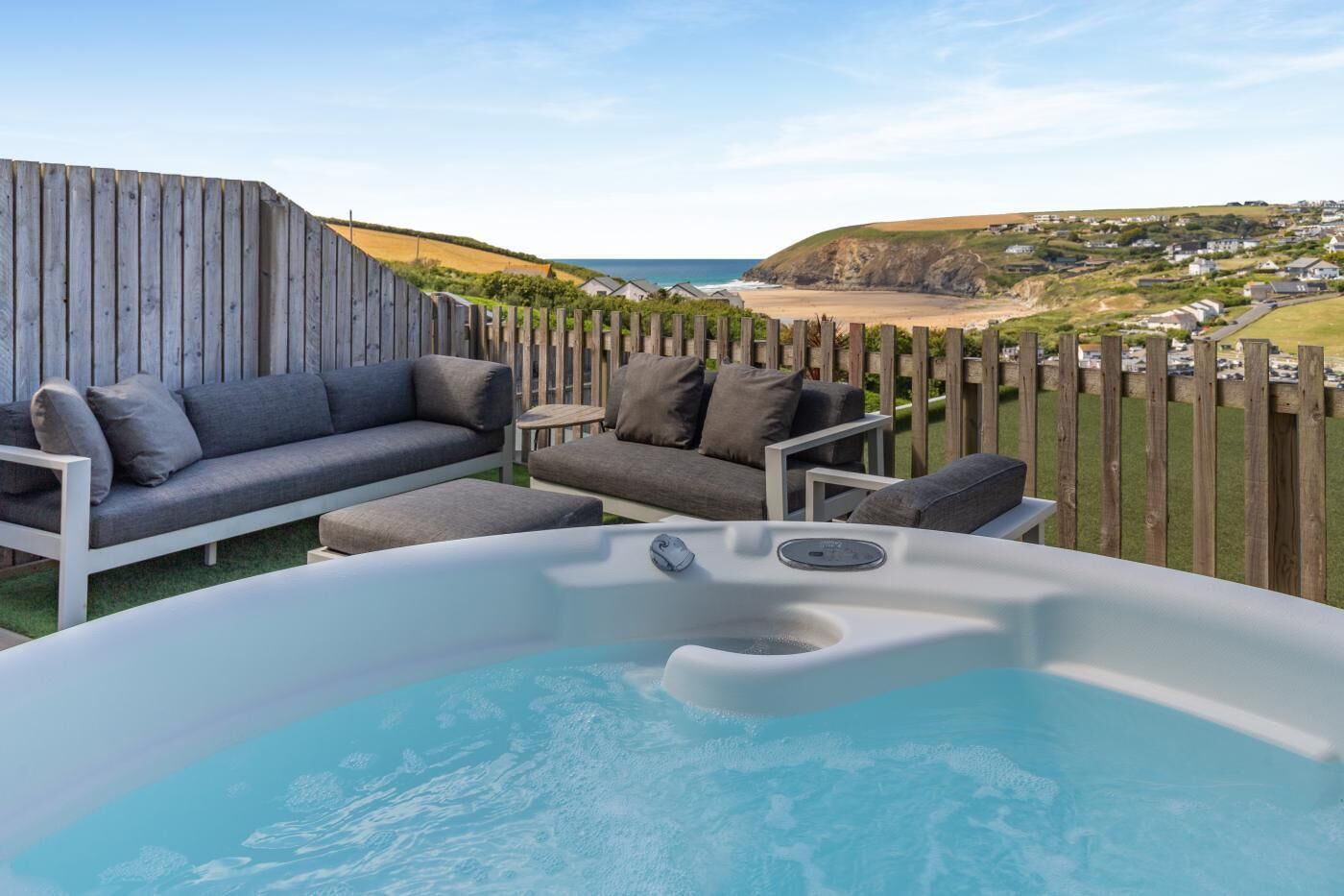 A hot tub with a view of the sea and a wooden fence.