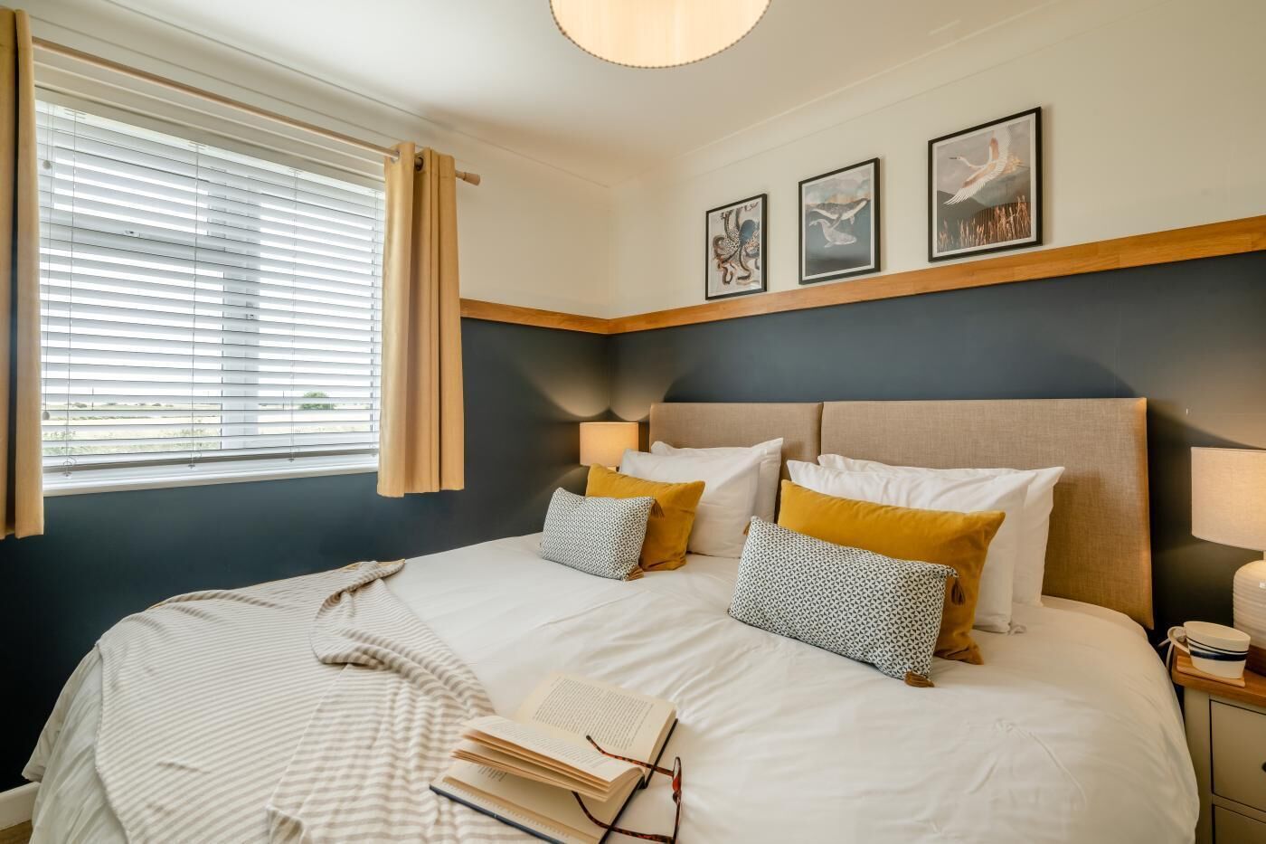 A hotel room with a large bed, a bedside table with a lamp, and a window with blinds.