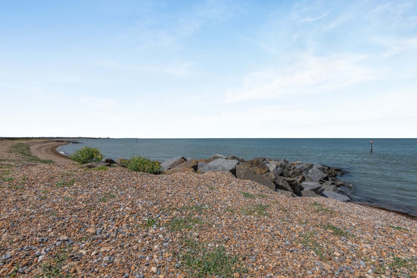 Ein Kiesstrand mit felsigem Ufer und ruhiger See.