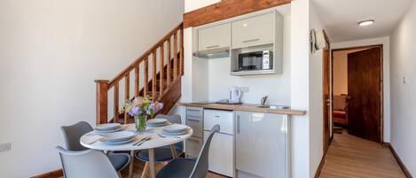 Una cocina moderna con microondas, lavamanos y escalera de madera.
