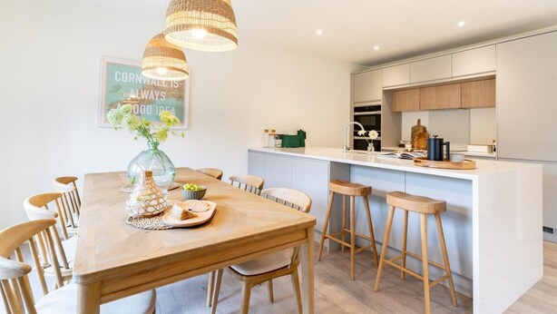Una cocina moderna con una isla central, sillas de madera e iluminación colgante.
