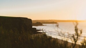 Paisaje costero con acantilados y una masa de agua al atardecer.