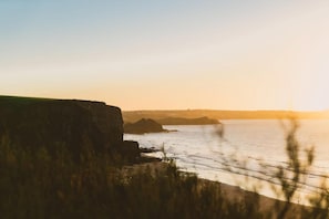 A coastal landscape with cliffs and a body of water during sunset. - 3 Bed in Watergate Bay (oc-b642096) (Tregurrian)