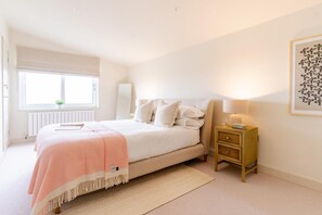 A bedroom with a bed, bedside table, lamp, and a window with a view. - 3 Bed in Watergate Bay (oc-b642096) (Tregurrian)