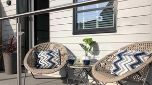 A balcony with two wicker chairs, a small table, and a potted plant. - 4 Bed in Porth (oc-b584252) (Newquay)
