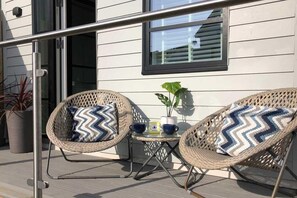 Ein Balkon mit zwei Korbstühlen, einem kleinen Tisch und einem Blumentopf.
