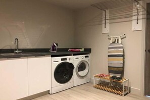 Eine kleine Küche mit Waschmaschine, Spüle und Wäscheständer.