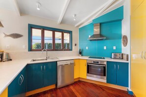 Eine moderne Küche mit türkisfarbenen und gelben Schränken, Edelstahlgeräten und einem Fenster mit Blick.