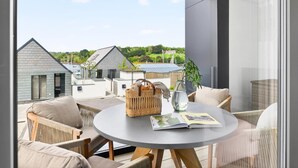 A modern outdoor seating area with a round table, wicker basket, and a vase. - 2 Bed in Falmouth (oc-b669230) (Flushing)