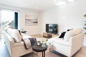 Ein modernes Wohnzimmer mit einer Couch, einem Couchtisch, einem Fernseher und einem Gemälde an der Wand.