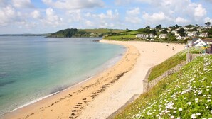 A coastal beach with a sandy shore, a grassy embankment, and houses in the background. - 2 Bed in Falmouth (oc-b669230) (Flushing)