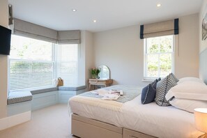 Ein Schlafzimmer mit Bett, Nachttisch, Fensterbank und Kommode.