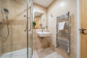 Ein modernes Badezimmer mit einer Duschkabine aus Glas, einem weißen Waschbecken und einem Handtuchhalter.