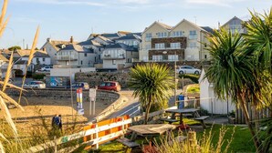 A coastal residential area with houses, a sandy beach, and a clear sky. - 2 Bed in Porth (oc-b588797) (Newquay)